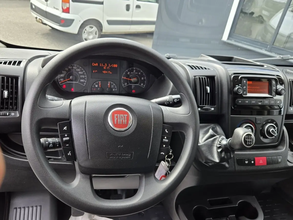 Vue intérieure centrée sur le volant noir FIAT et le tableau de bord du fourgon blanc FIAT Ducato 2023.