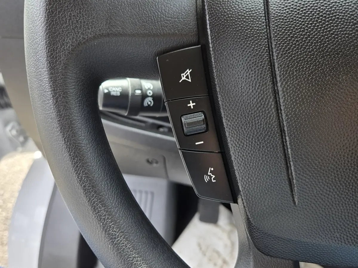 Gros plan sur les commandes du volant noir du Fiat Ducato Fourgon blanc, version 2023, avec régulateur de vitesse.