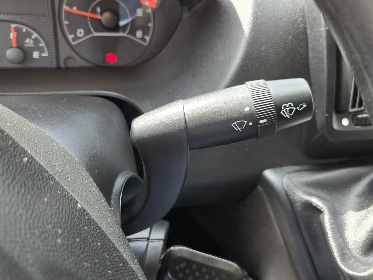 Gros plan sur la manette d’essuie-glace du tableau de bord du Fiat Ducato Fourgon blanc, intérieur noir.