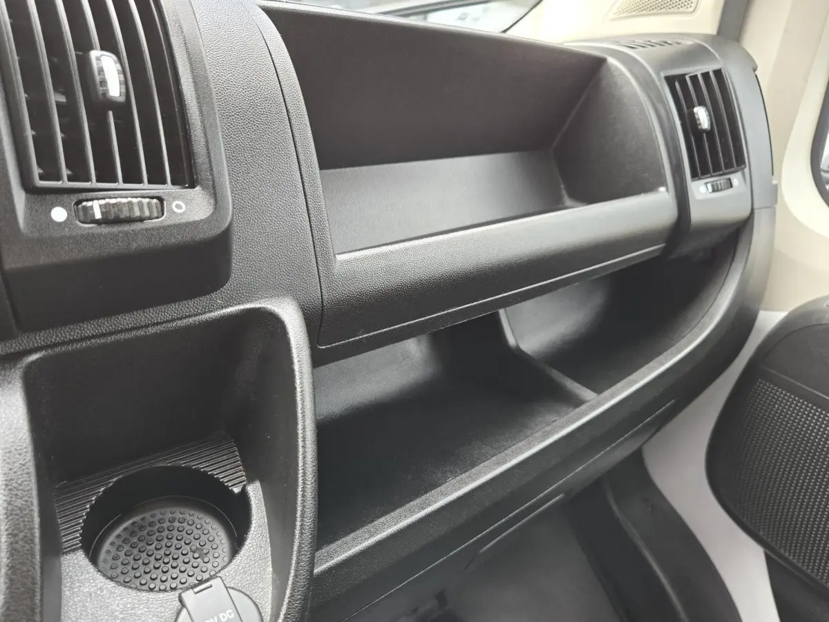 Vue rapprochée de la console centrale noire du Fiat Ducato Fourgon 2023, avec porte-gobelet et aérateurs.