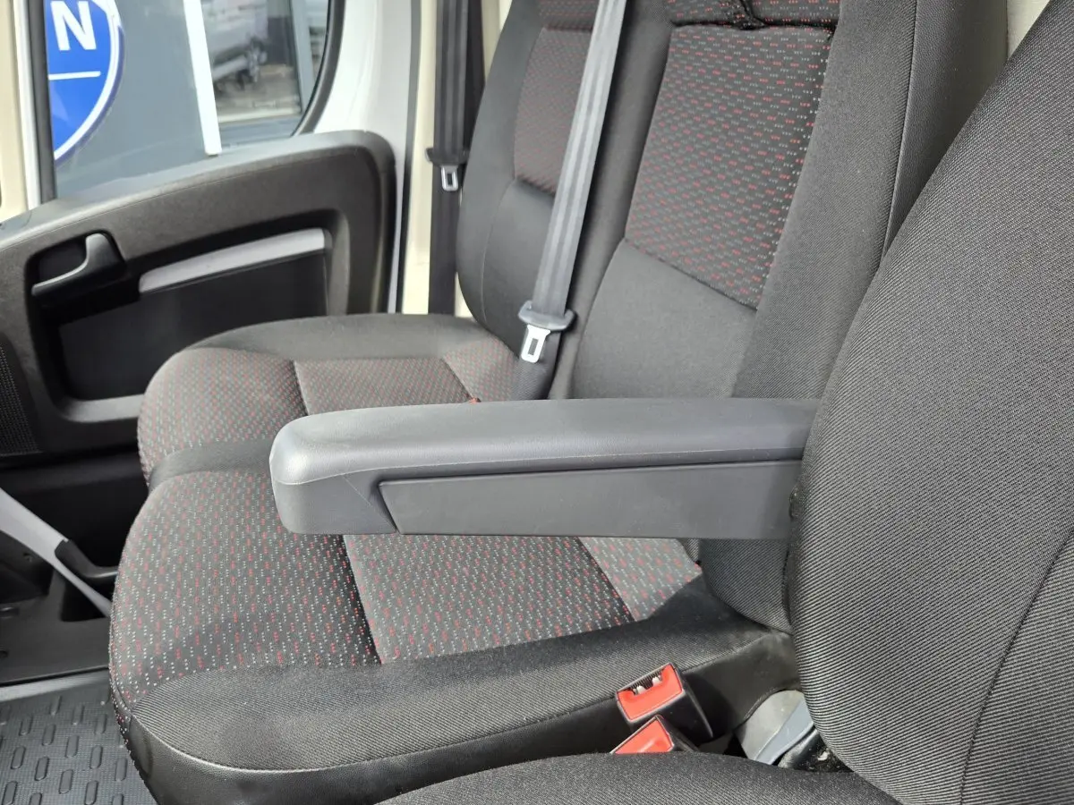 Gros plan sur les sièges avant gris foncé avec motifs rouges du Fiat Ducato Fourgon, côté conducteur, avec accoudoir relevé.