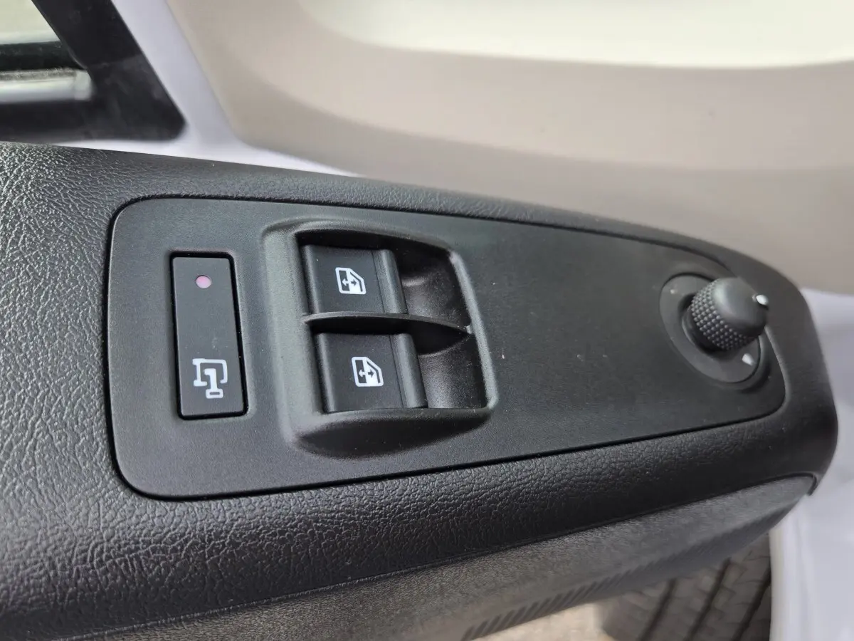 Gros plan sur les commandes de lève-vitres et réglage des rétroviseurs côté conducteur du Fiat Ducato Fourgon blanc.