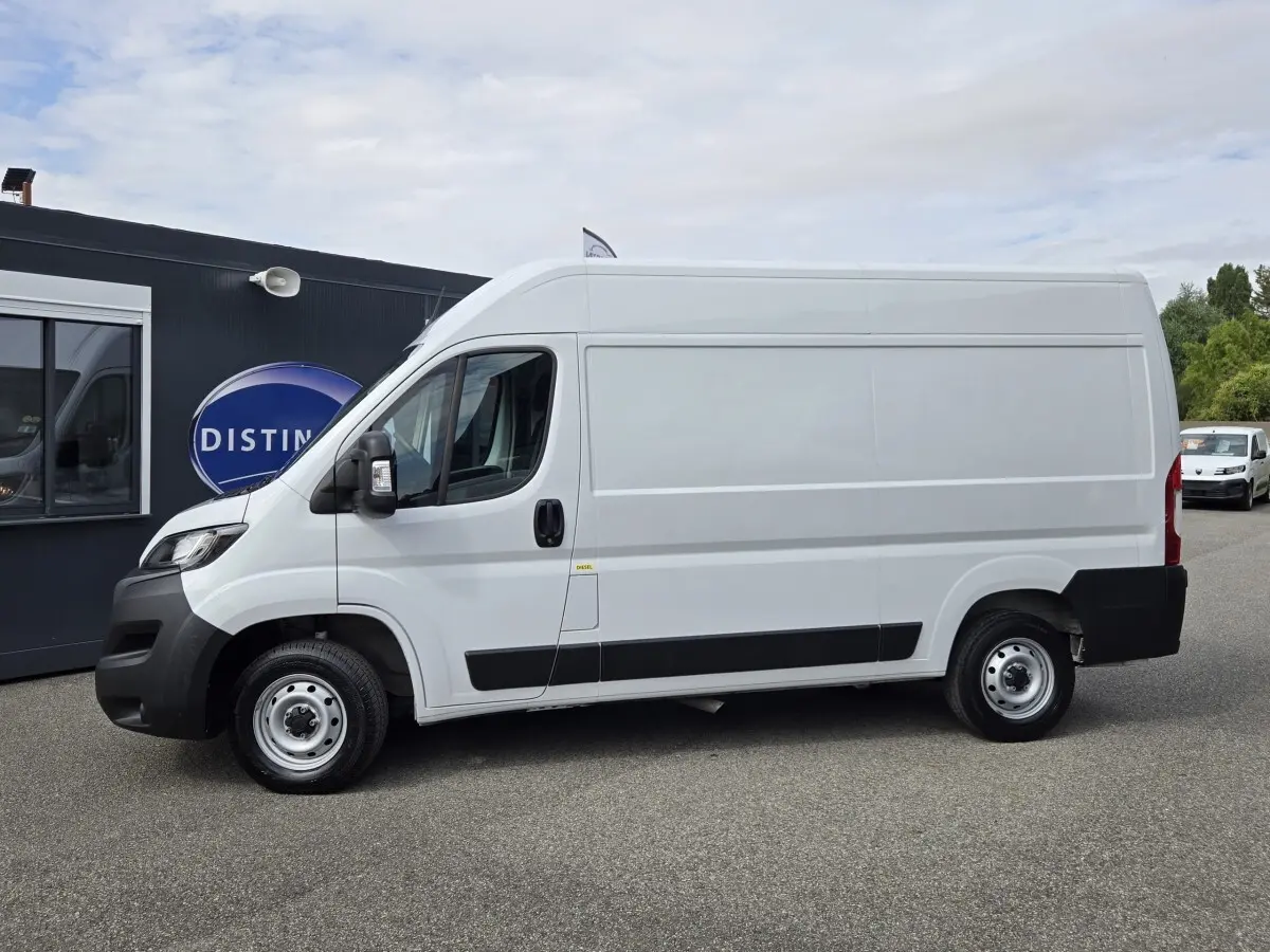 Vue latérale gauche d’un FIAT Ducato Fourgon blanc 2023 avec bas de caisse noir et jantes acier.