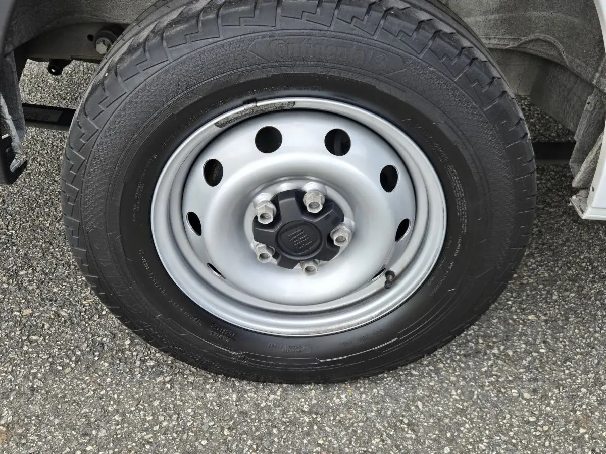 Gros plan sur la roue avant droite du FIAT Ducato Fourgon blanc, avec jante acier et logo central FIAT.