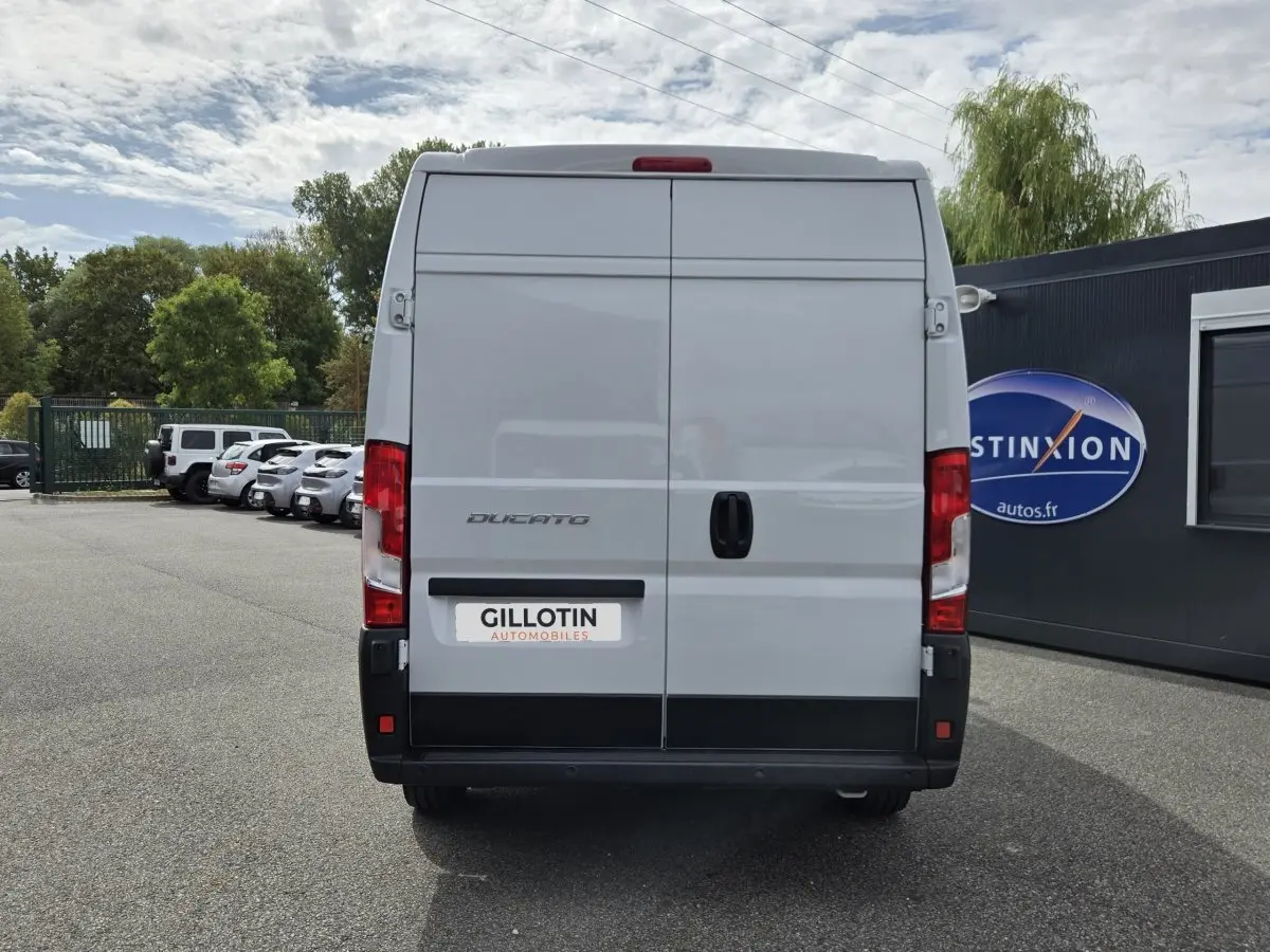 Vue arrière d’un FIAT Ducato Fourgon blanc 2023 avec portes arrière fermées et feux rouges visibles.