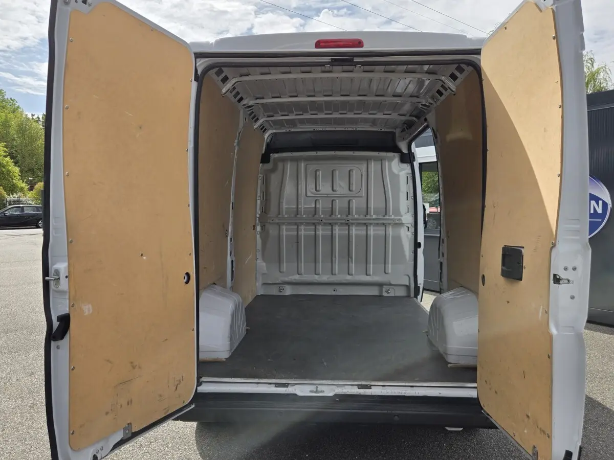 Vue arrière du FIAT Ducato Fourgon blanc 2023 avec portes ouvertes montrant l’intérieur vide et cloison pleine.