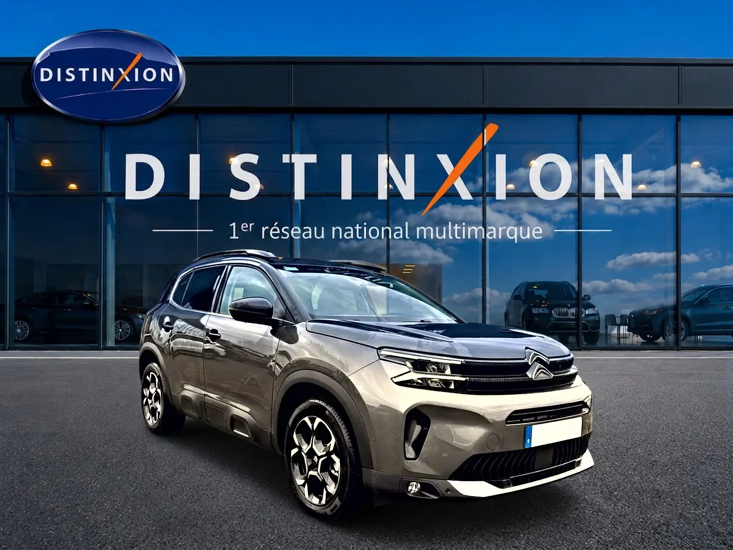 Citroën C5 Aircross gris platinium vue 3/4 avant avec jantes alu et barres de toit devant showroom Distinxion.