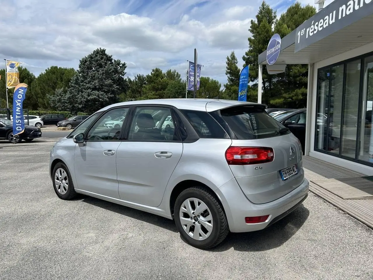Vue 3/4 arrière droite d'une Citroën C4 Picasso gris aluminum de 2016, avec feux arrière rouges et jantes alliage.