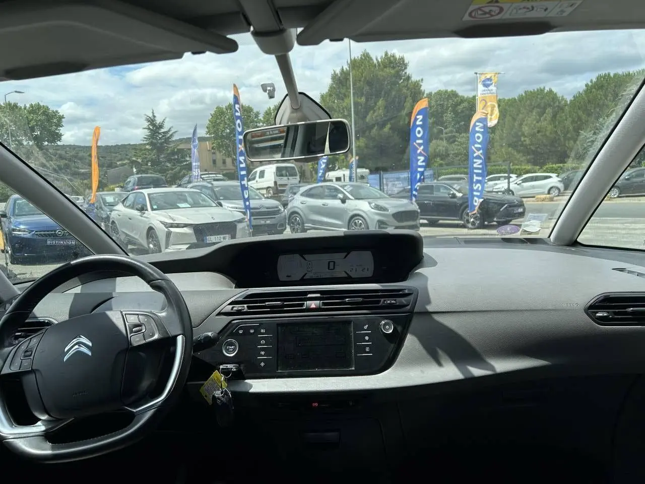 Vue intérieure du tableau de bord et volant du Citroën C4 Picasso gris aluminum, avec écran central et commandes visibles.