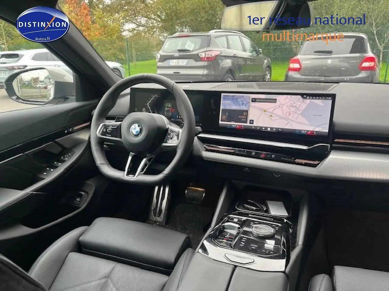 Intérieur de BMW Série 5 (G60) 520da 2024, vue du poste de conduite avec écran tactile large et volant cuir noir.