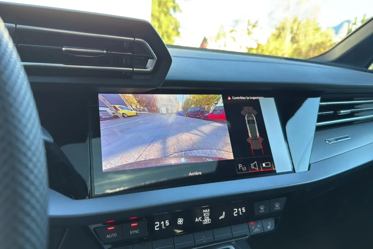 Vue intérieure du tableau de bord de l'Audi A3 2025 noir mythic avec écran caméra de recul et climatisation digitale.