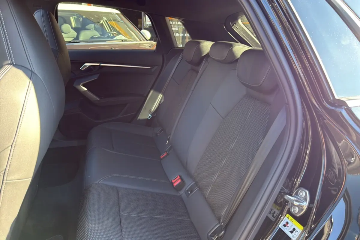 Vue côté gauche des sièges arrière en cuir tissu noirs de l'Audi A3 TFSI 150 Hybrid S-Line 2025 avec portière ouverte.