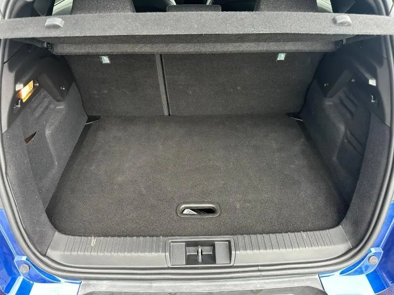 Vue du coffre ouvert du Renault Captur 1.6 E-Tech bleu Iron avec intérieur noir et cache-bagages relevé.