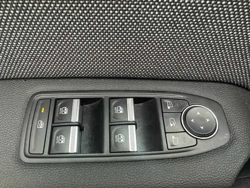 Gros plan sur les commandes de lève-vitres et réglages des rétroviseurs côté conducteur du Renault Captur bleu Iron/Noir Etoilé.