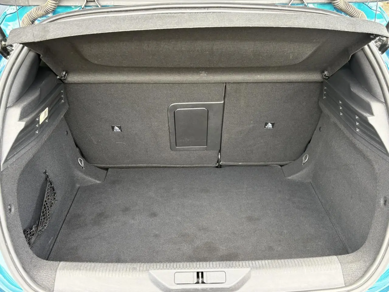 Coffre ouvert vu de l'arrière de la Peugeot 308 Bleu Obsession, montrant un espace de rangement propre et spacieux.