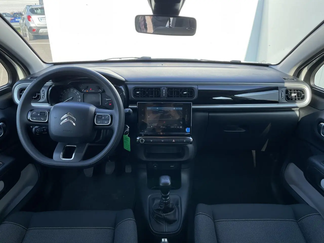 Vue frontale de l'intérieur noir de la Citroën C3 2024 avec tableau de bord moderne et écran tactile central.