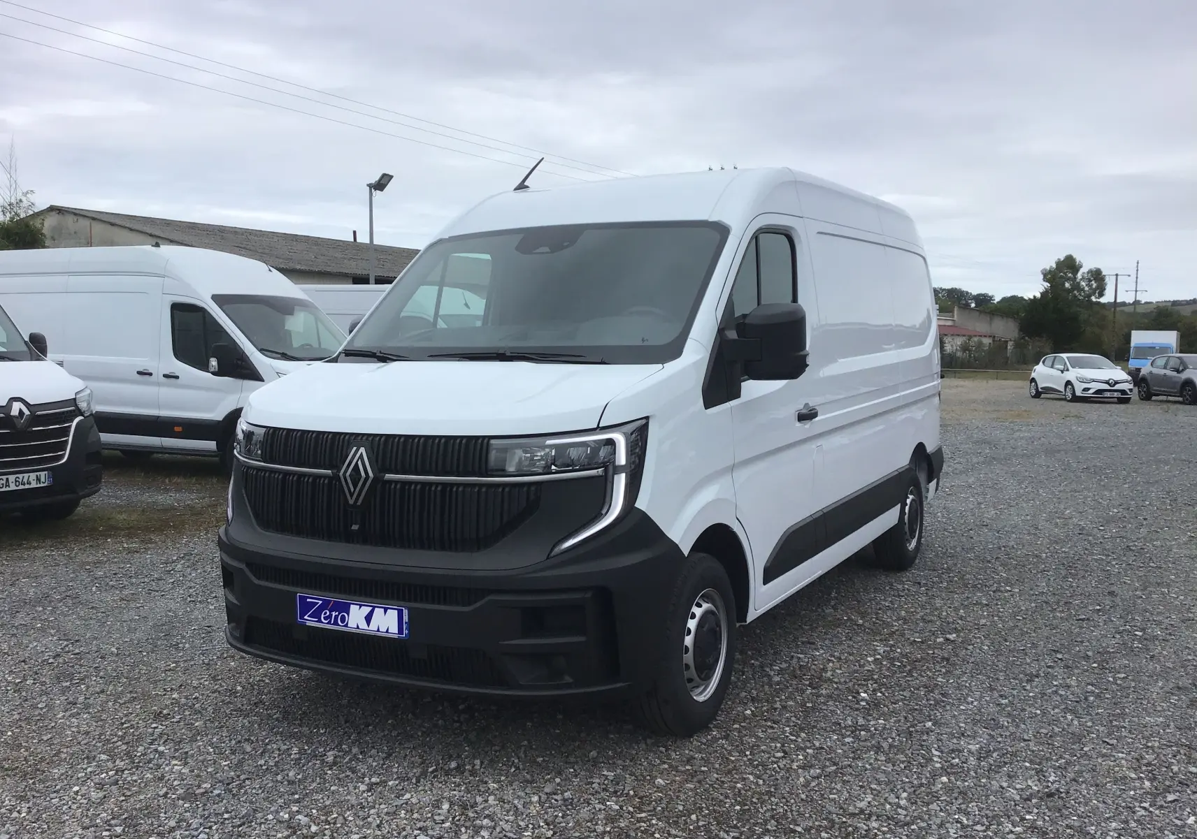 Renault Master blanc en 3/4 avant droit sur parking, avec calandre noire et pare-chocs contrasté visible