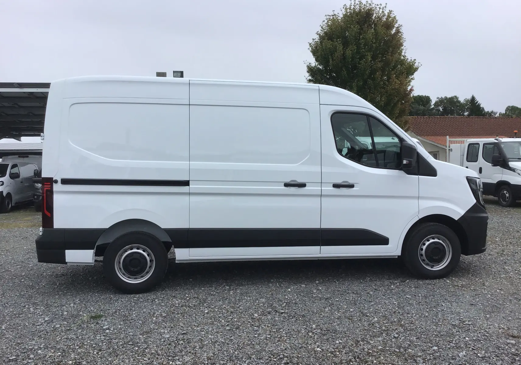 Profil latéral droit d’un utilitaire Renault Master blanc, version L2H2, avec protections noires sur les bas de caisse et roues acier.