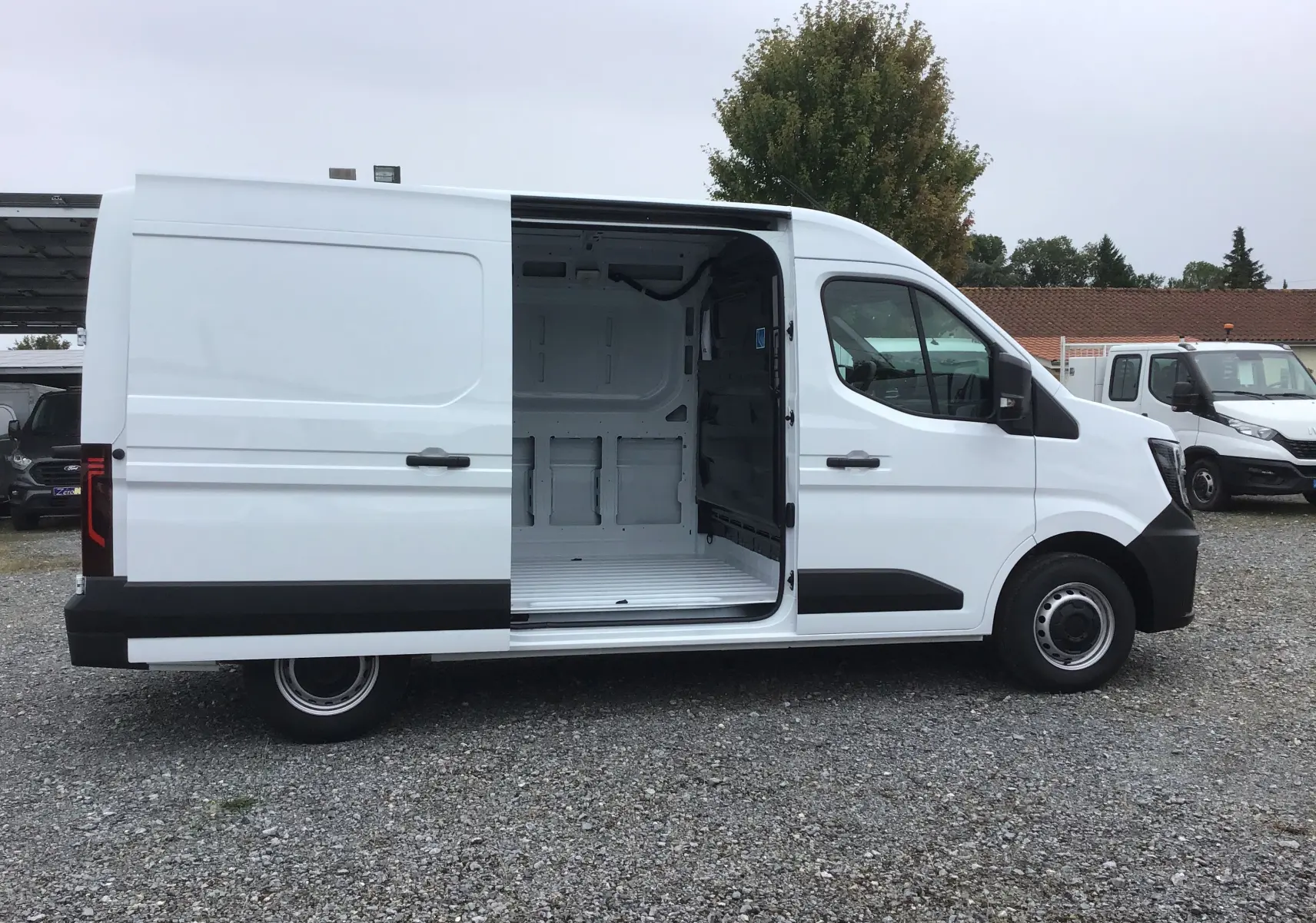 Renault Master blanc vu de profil côté gauche, porte latérale coulissante ouverte montrant l'espace de chargement vide.