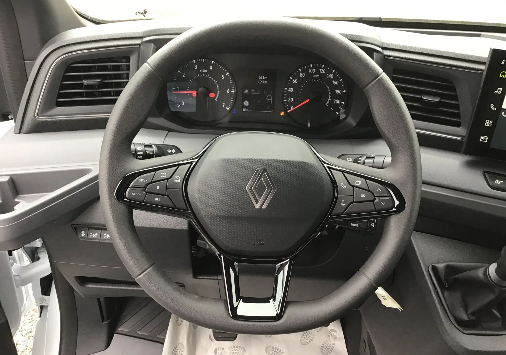 Vue intérieure centrée sur le volant noir du Renault Master blanc 2025 avec tableau de bord et commandes intégrées.