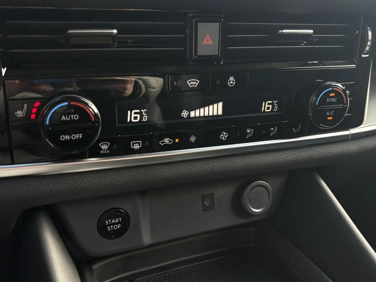Vue rapprochée de la console centrale du Nissan Qashqai III noir, affichant la climatisation automatique bi-zone à 16°C.