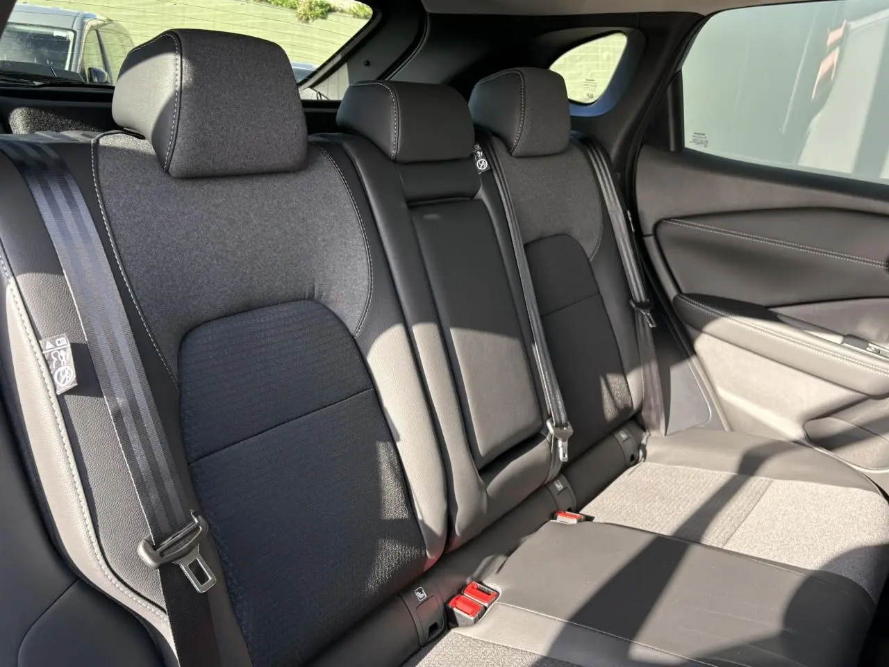 Vue intérieure côté droit des sièges arrière gris foncé du Nissan Qashqai III e-Power 2025 avec ceinture de sécurité visible.