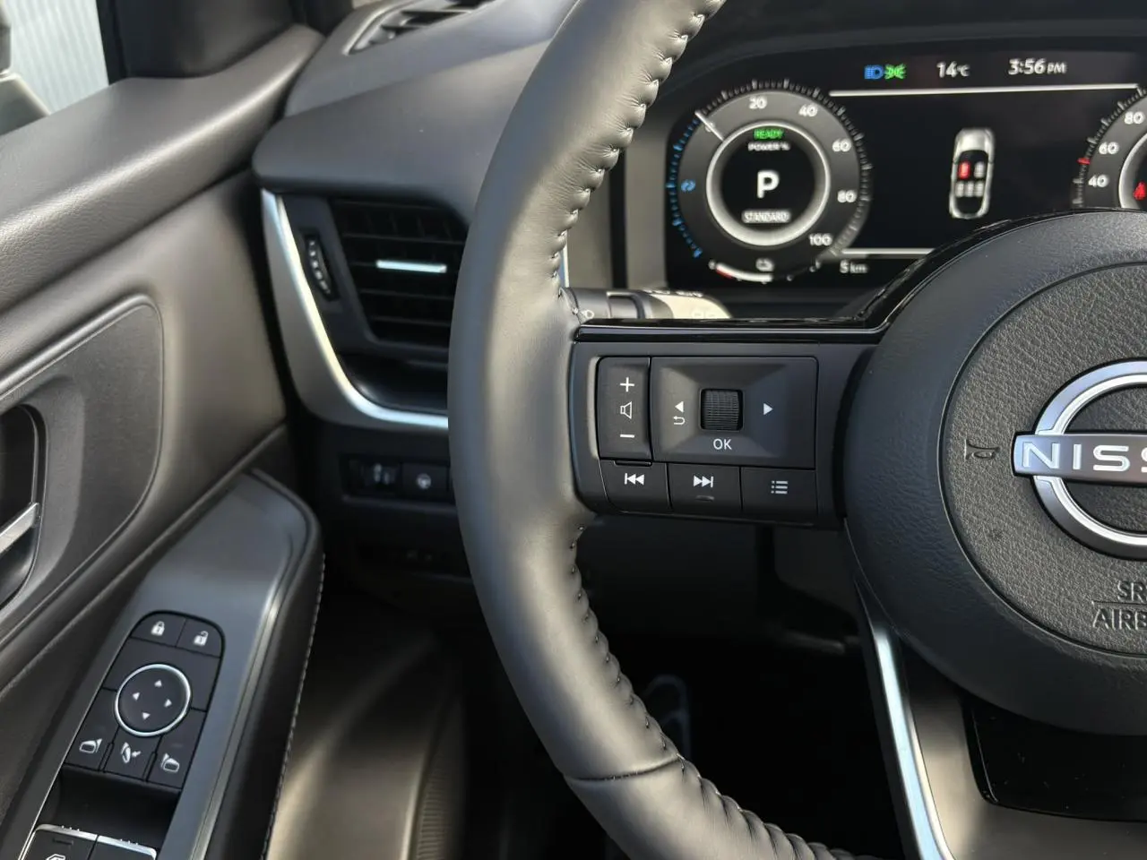 Gros plan sur le volant cuir et la porte côté gauche du Nissan Qashqai noir, avec tableau de bord numérique visible.