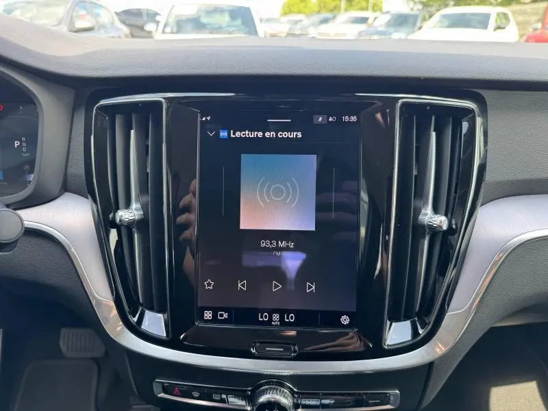 Vue rapprochée du tableau de bord noir et gris du Volvo S60 2024, avec écran tactile central allumé affichant la radio FM.