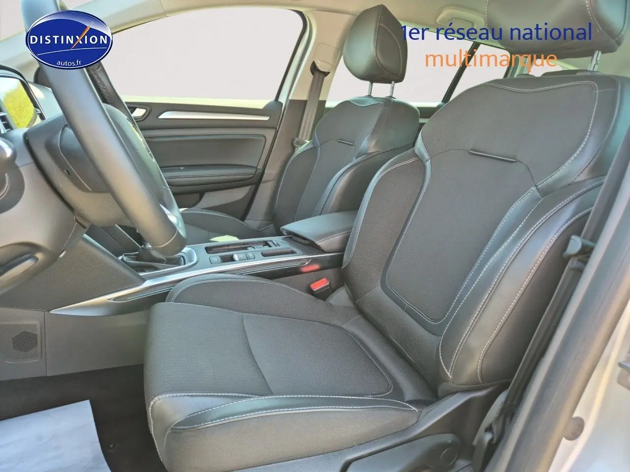 Vue intérieure côté conducteur de la Renault Mégane Break 2024, sièges tissu gris foncé avec surpiqûres blanches.