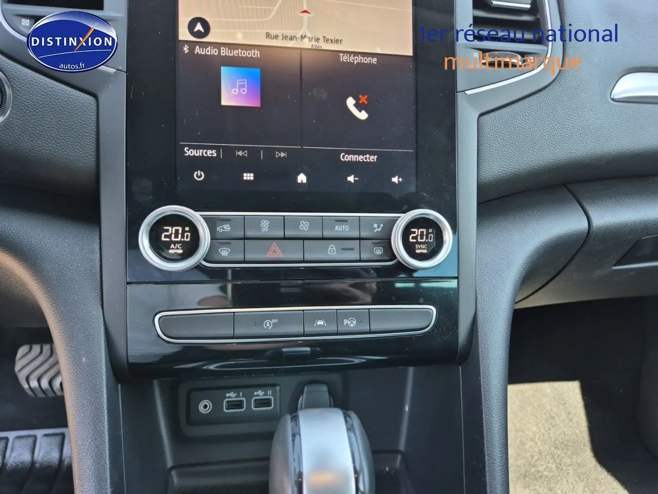 Vue rapprochée de la console centrale et levier de vitesse de la Renault Mégane Break gris Titanium, avec écran tactile et commandes clim.