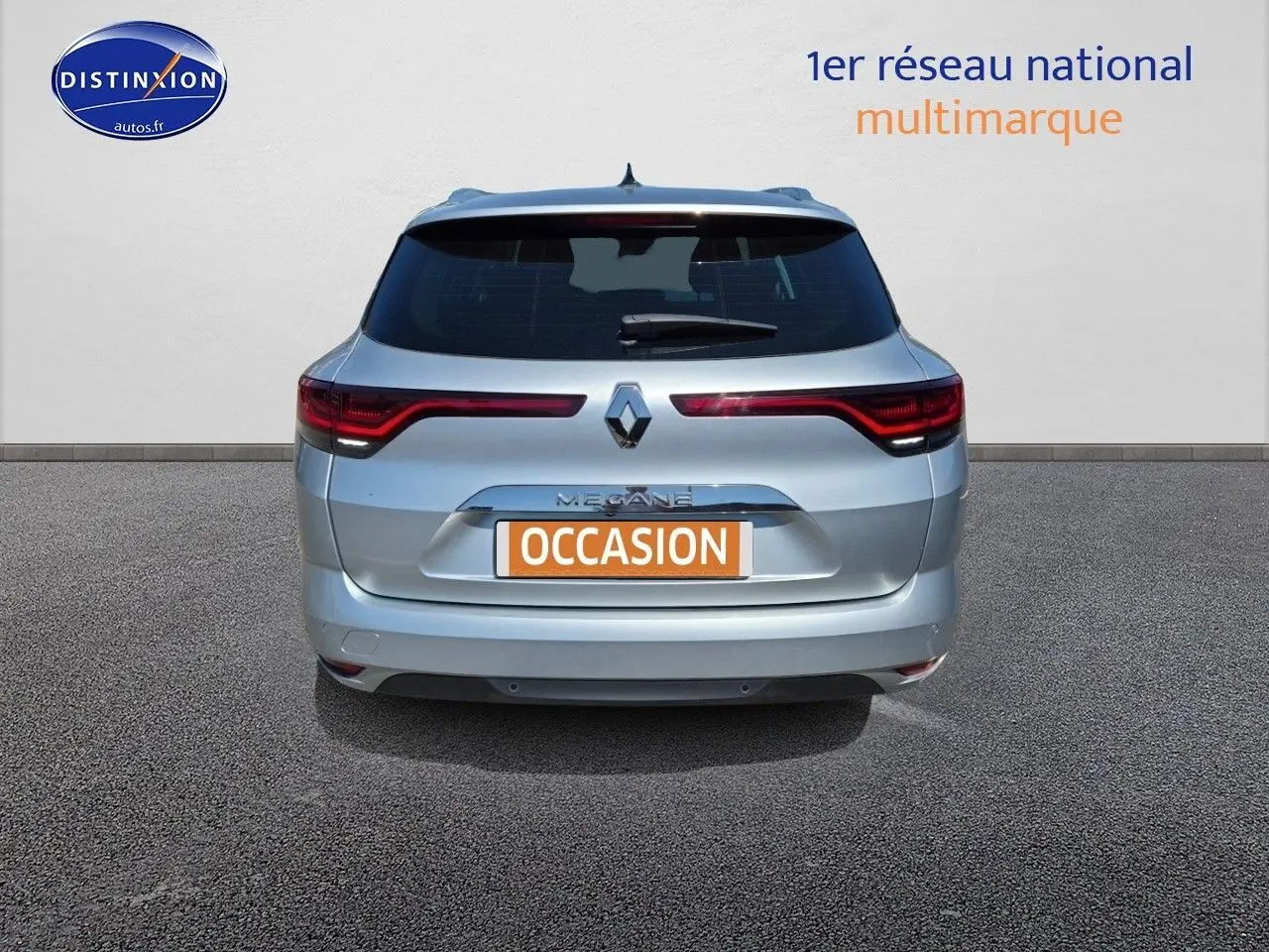 Vue arrière d'une Renault Mégane Break 2024 gris titanium avec feux arrière LED et barres de toit visibles.