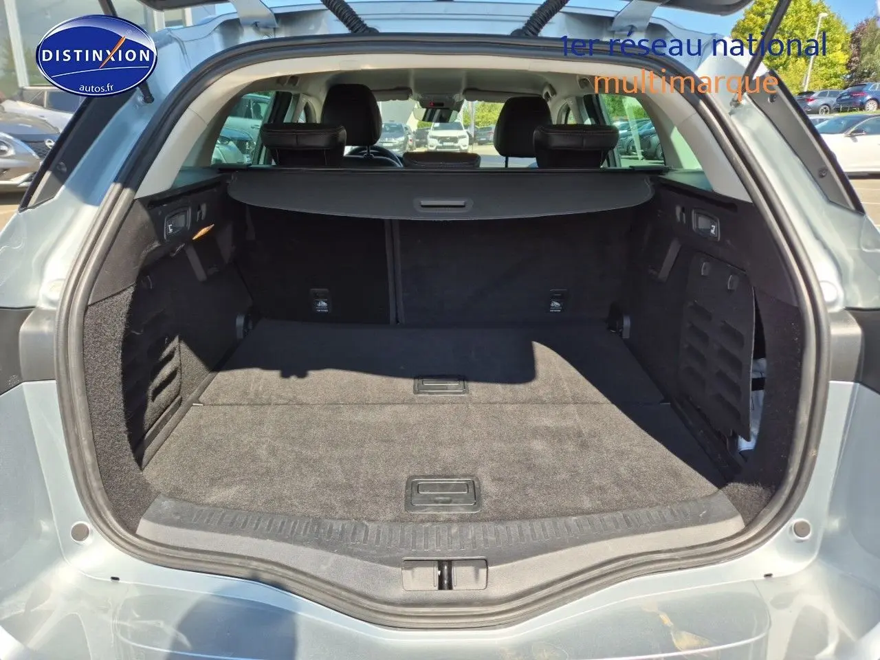 Coffre ouvert vu de l'arrière d'une Renault Mégane Break gris titanium, montrant un espace de chargement spacieux et propre.