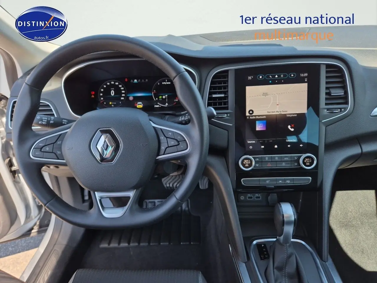 Vue intérieure avant centrée sur le volant multifonction et l'écran tactile du tableau de bord de la Renault Mégane Break 2024.