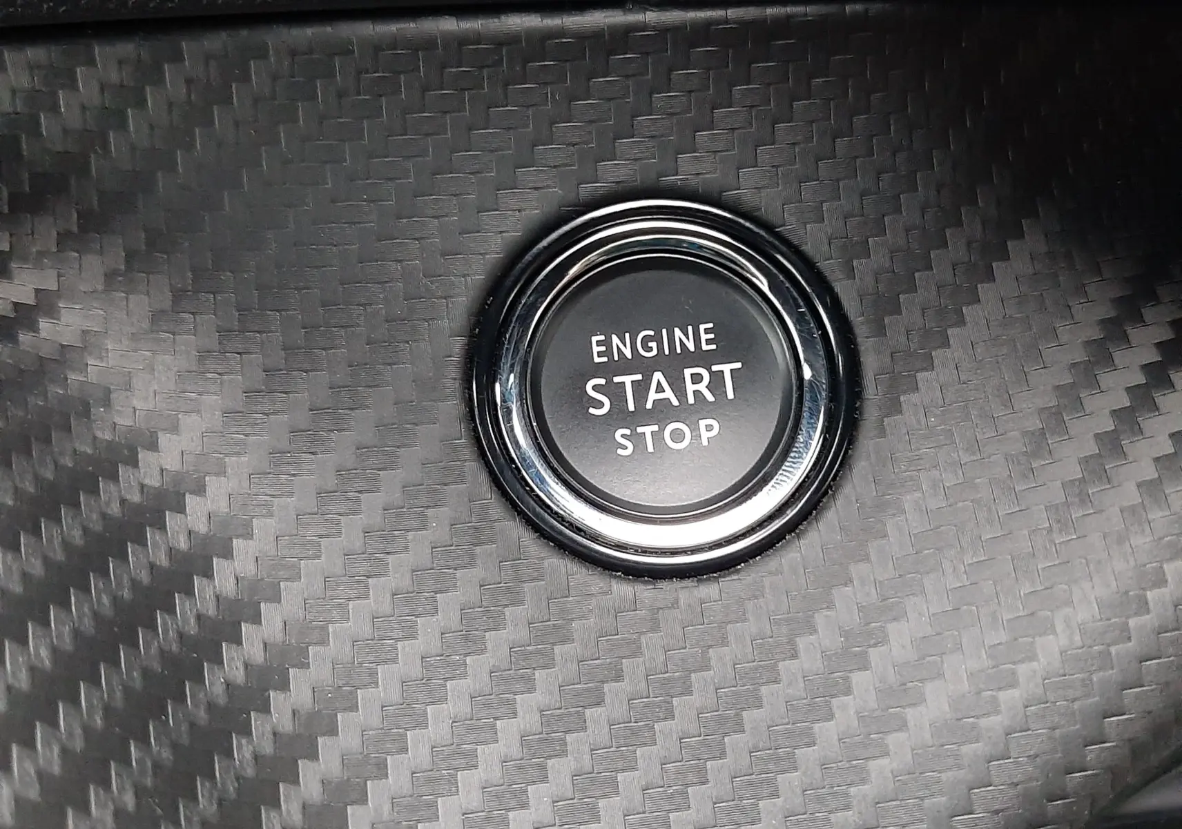 Bouton start/stop moteur sur tableau de bord en carbone du Peugeot 2008 GT blanc nacré toit noir.