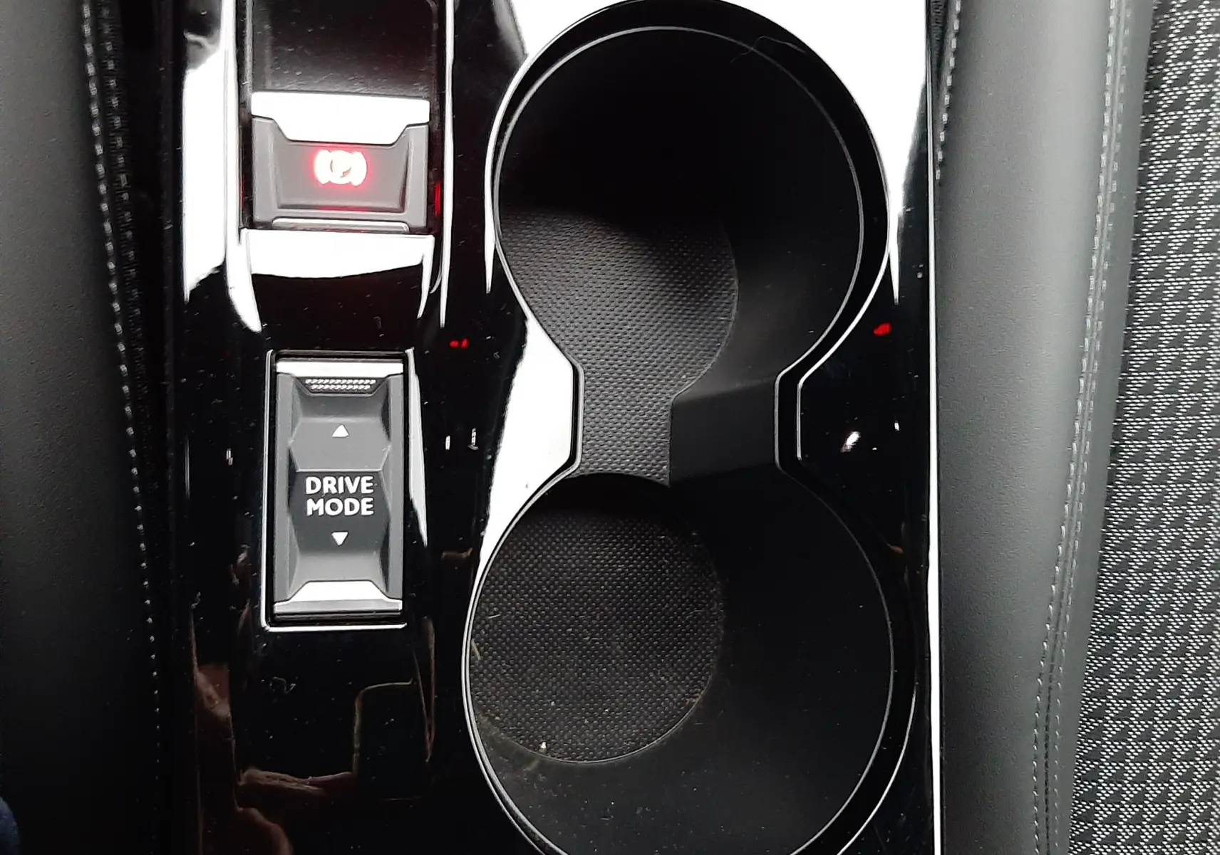 Gros plan sur la console centrale noire brillante du Peugeot 2008 2023 avec porte-gobelets et bouton Drive Mode.