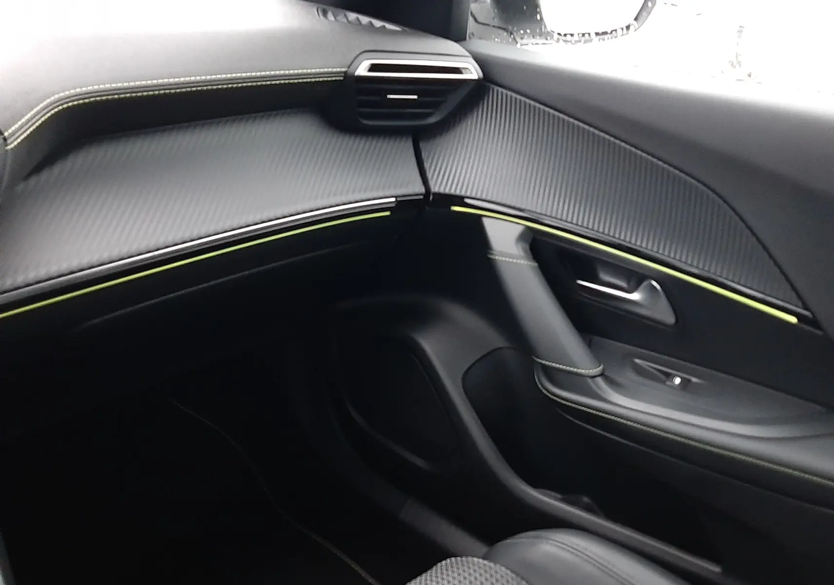 Intérieur côté passager du Peugeot 2008 2023, avec tableau de bord noir texturé et surpiqûres vertes, siège tissu et cuir.