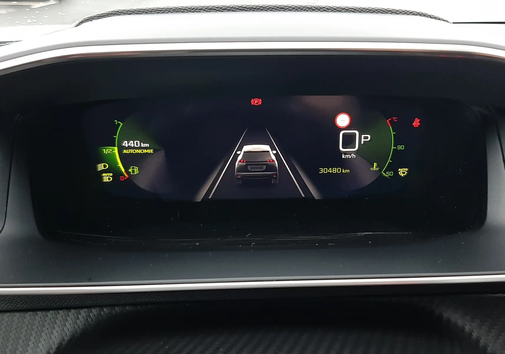 Tableau de bord numérique du Peugeot 2008 2023 affichant la vue arrière du véhicule blanc nacré en stationnement.