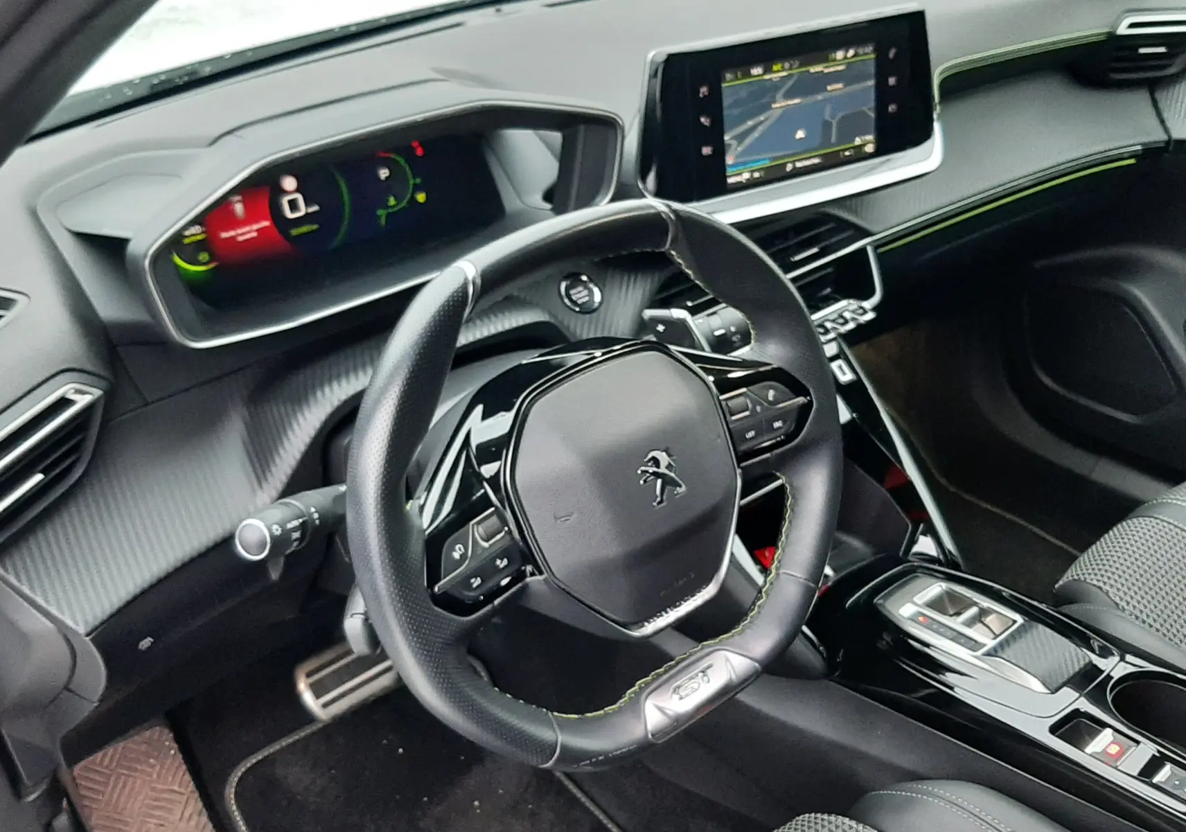 Intérieur du Peugeot 2008 2023 vu côté conducteur, volant GT avec surpiqûres vertes et écran tactile central.