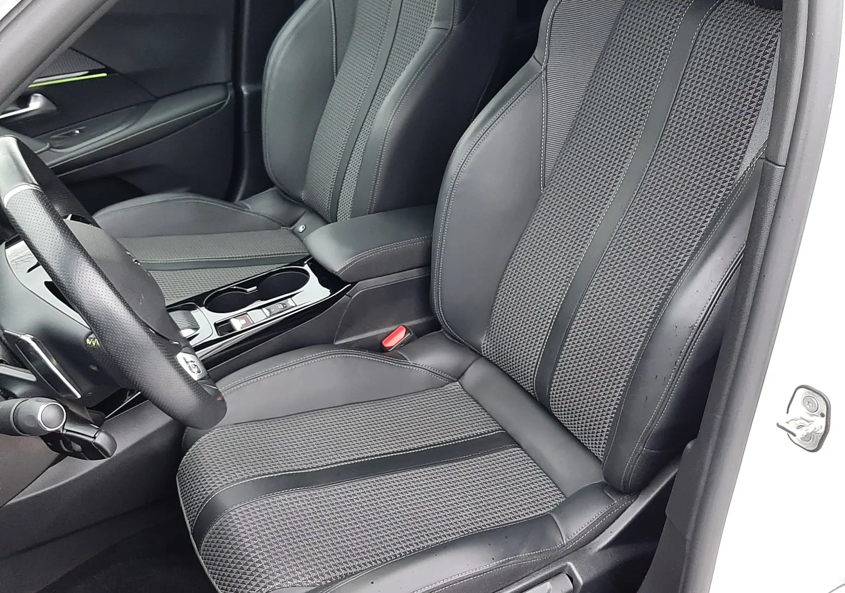 Vue intérieure côté conducteur du Peugeot 2008 2023 avec sièges en cuir noir et tissu, volant multifonction et console centrale.