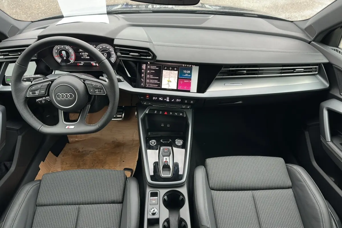 Vue intérieure de l'Audi A3 2025 TFSI 150 Hybrid S-Line, tableau de bord et console centrale modernes en noir.