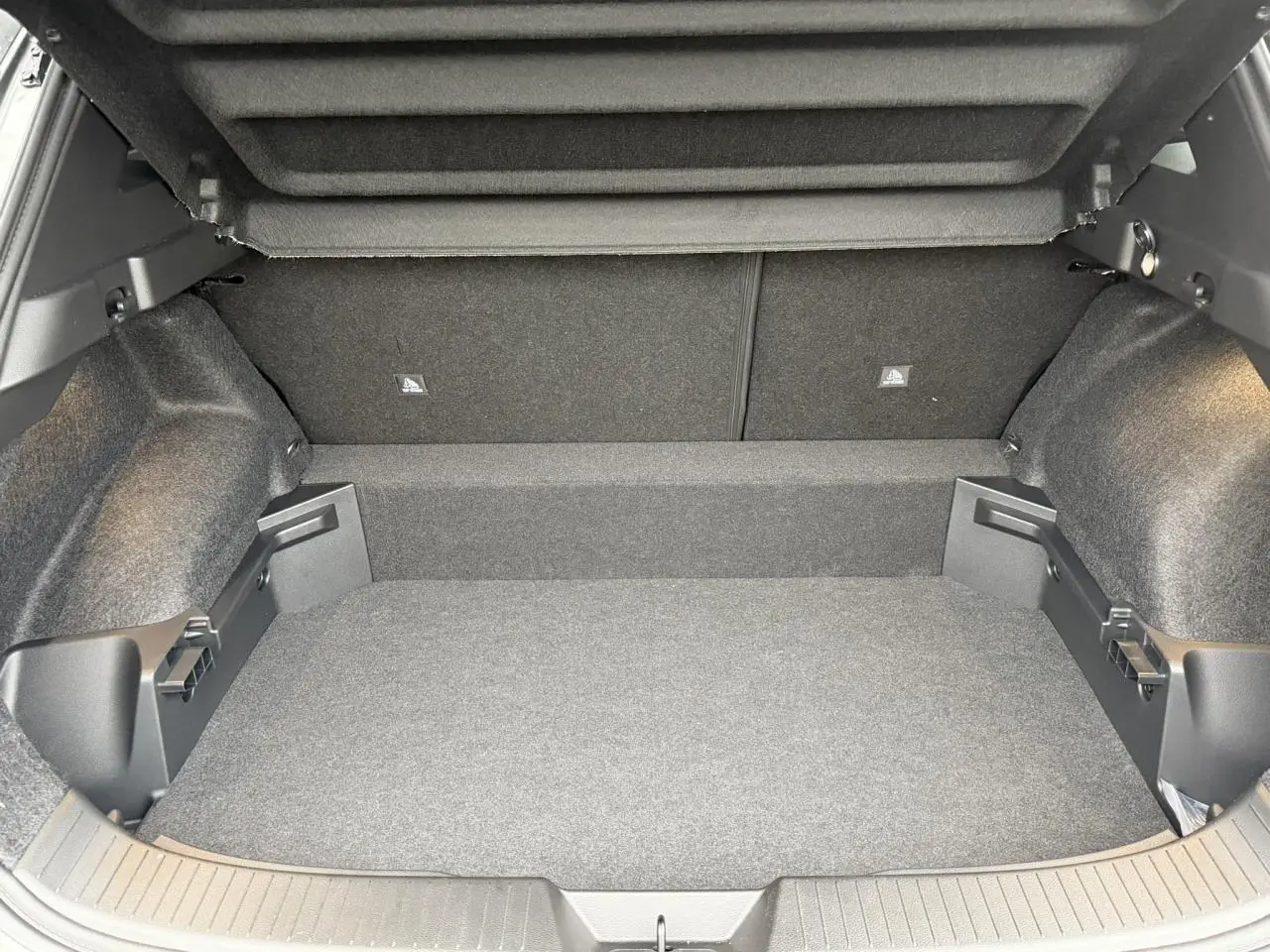 Coffre ouvert en vue arrière d'un Nissan Qashqai III e-Power gris Squale, montrant un espace de chargement vide et propre.