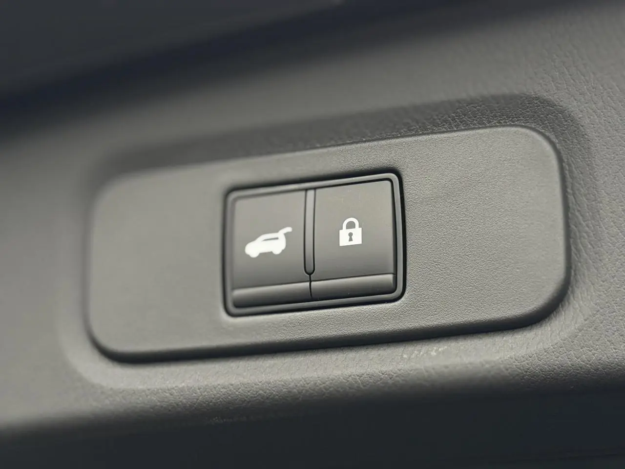 Gros plan sur les boutons d'ouverture électrique du hayon et de verrouillage dans l'habitacle du Nissan Qashqai gris Squale 2025.