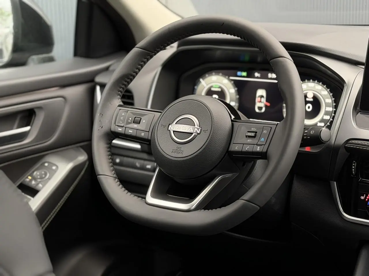 Vue rapprochée du volant cuir noir et du tableau de bord numérique du Nissan Qashqai III gris Squale, version 2025.