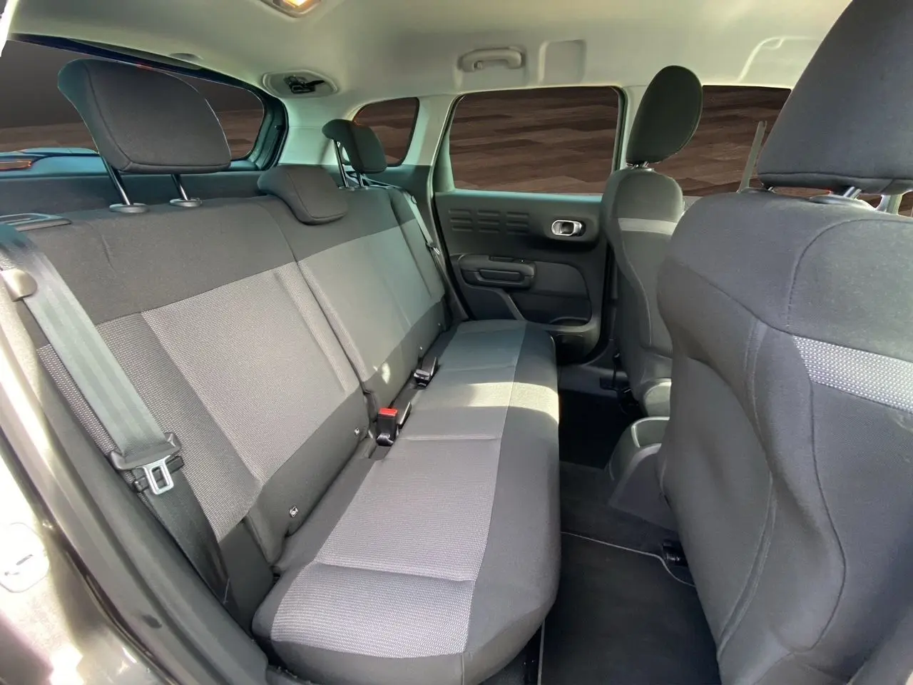 Vue intérieure arrière côté gauche du Citroën C3 Aircross 2022, sièges tissu gris et noir, habitacle spacieux.