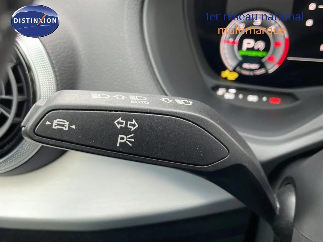 Gros plan sur la manette de clignotant noire avec symboles blancs dans l'habitacle d'un Audi Q2 35 2.0 TDI argent rose métal.