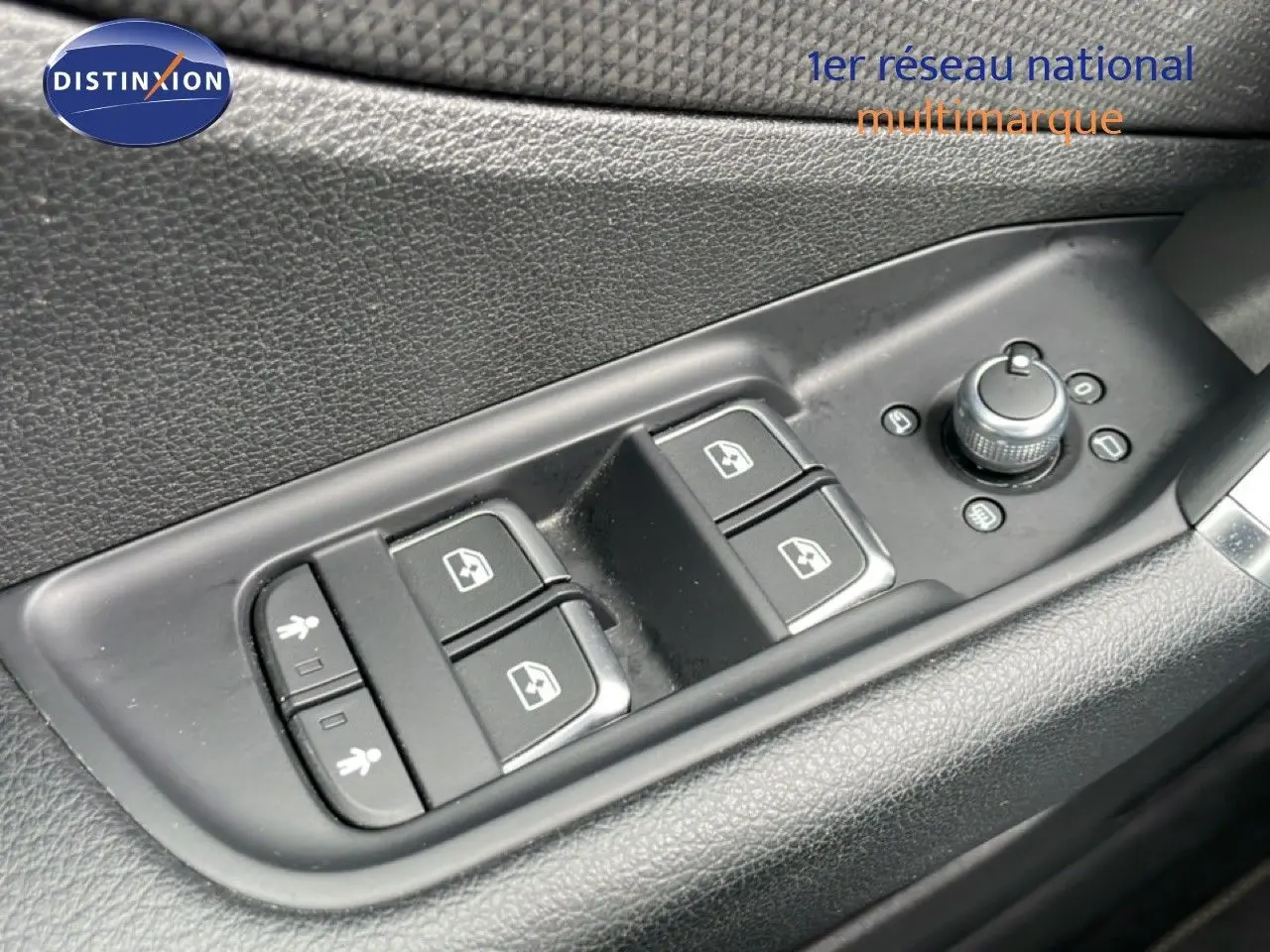 Gros plan sur les commandes de lève-vitres et réglage des rétroviseurs côté conducteur d’un Audi Q2 argent rose.