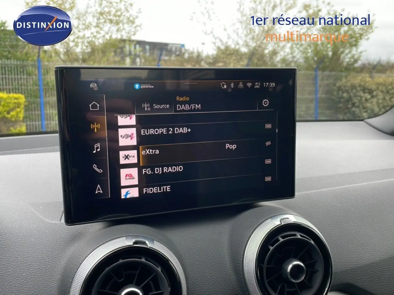 Écran tactile central affichant les stations radio DAB/FM dans l'habitacle d'un Audi Q2 argent rose 2025.