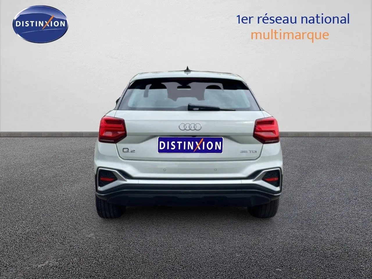 Vue arrière d'un Audi Q2 argent rose métal 2025 avec feux rouges et logo distinctif sur fond neutre.