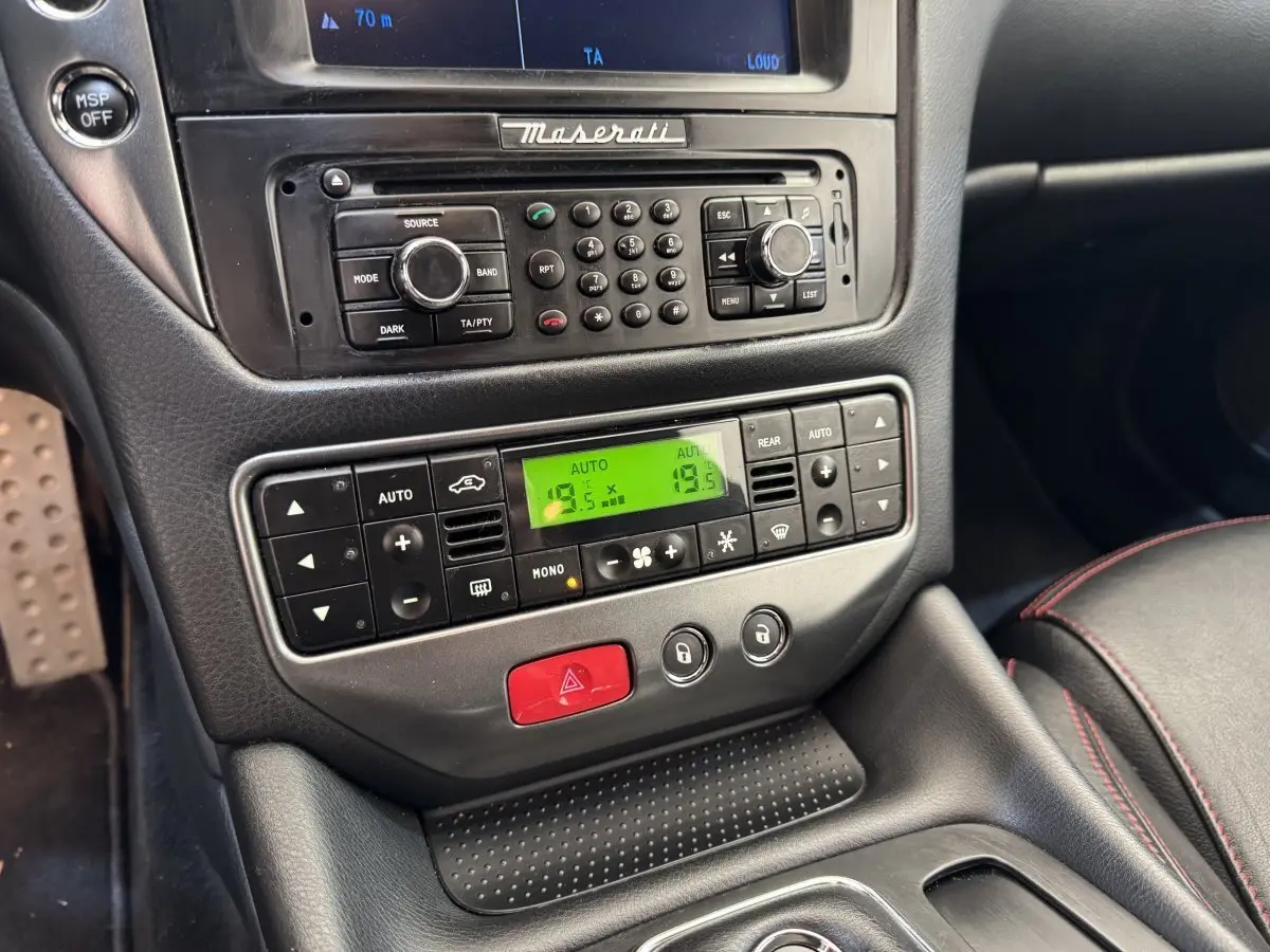 Vue rapprochée de la console centrale de la Maserati Granturismo S 4.7 2010, avec commandes climatisation et radio intégrées.