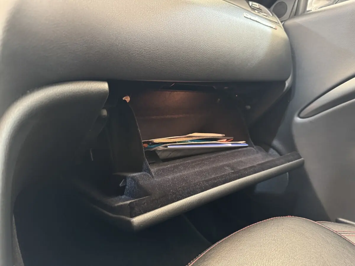 Gant de boîte à gants ouvert côté passager dans l’habitacle noir d’une Maserati Granturismo S 4.7 gris foncé 2010.